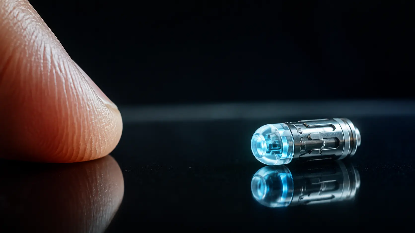 A tiny precision biometric device beside a fingertip on black glass
